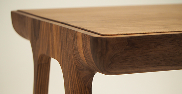 a bespoke table made out of mahogany sanded down with curved edges and a raised surface