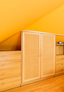 built in wardrobe on a slanted roof in a yellow room 