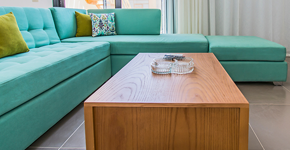 a bespoke wooden table with a glass ornament on top next to a blue corner sofa