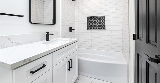 a white bathroom with white painted wooden cabinets and black handles